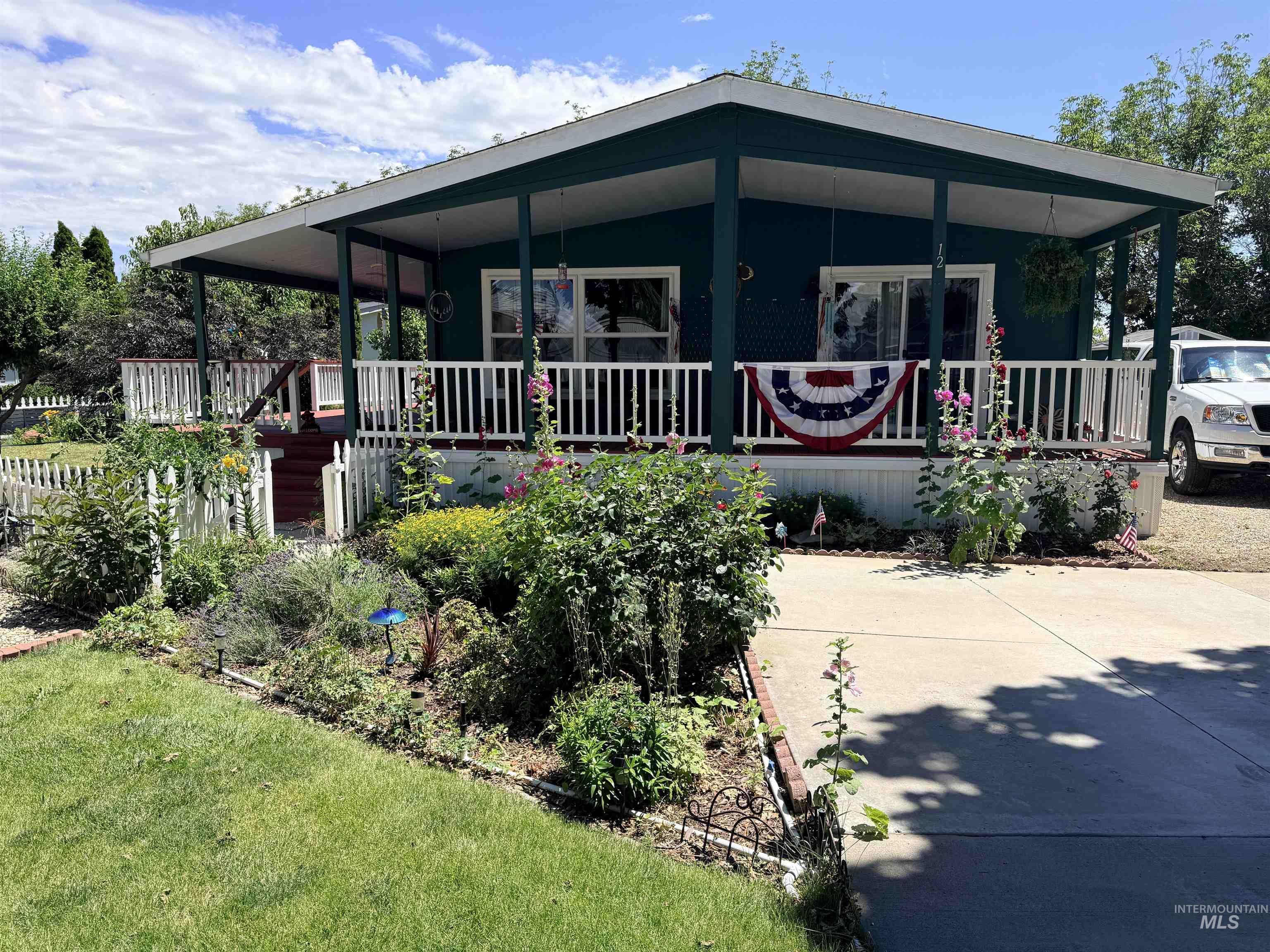 2750 Alden Road, Unit 12 12 Fruitland, ID 83619 - Photo 38 of 38 Front exterior featuring a covered porch with white railing, a mature landscaped garden, and a concrete driveway