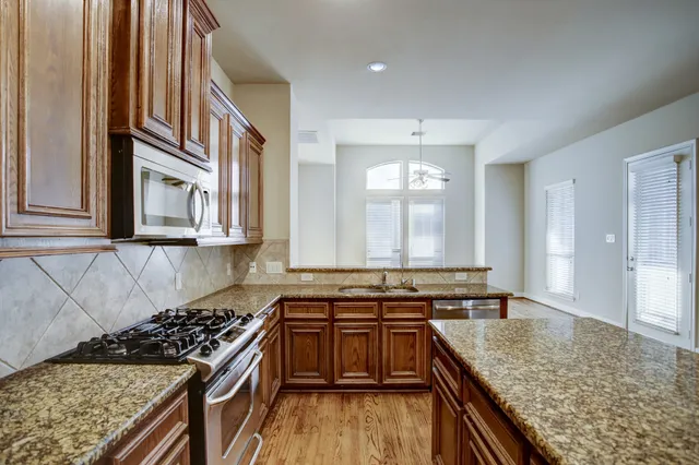 a kitchen with stainless steel appliances granite countertop a stove a sink and a refrigerator