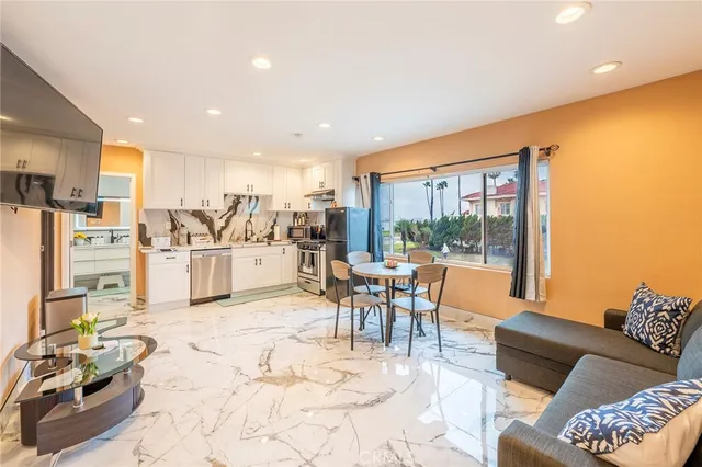 a living room with stainless steel appliances furniture a rug and a view of kitchen