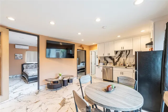 a kitchen with stainless steel appliances kitchen island granite countertop a refrigerator a stove a sink dishwasher with a dining table and chairs with wooden floor