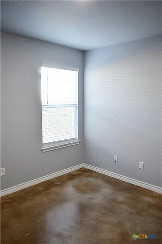 a view of an empty room with a window and hardwood floor