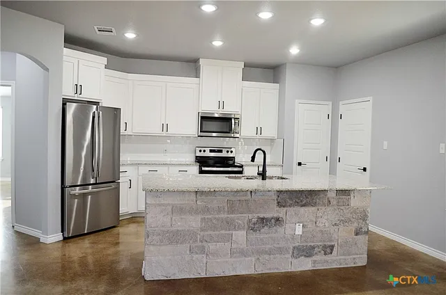 a kitchen with granite countertop a sink and cabinets