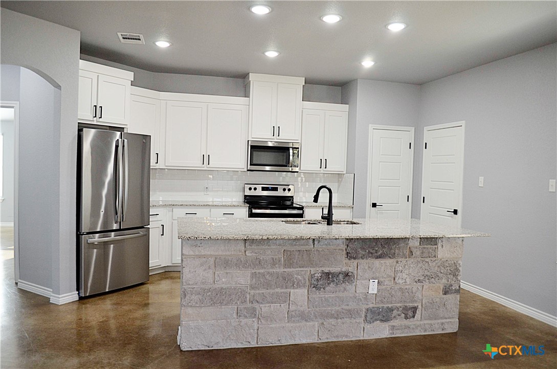 745 Freedom Circle Nolanville, TX 76559 - Photo 8 of 38 a kitchen with granite countertop a refrigerator and a stove top oven