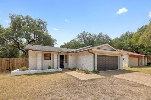 a view of a yard in front of a house with a large tree