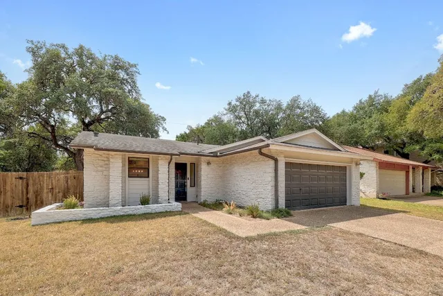 a view of a yard in front of a house with a large tree