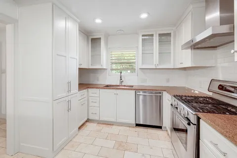 a kitchen with white cabinets and appliances