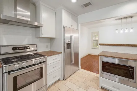 a kitchen with cabinets stainless steel appliances and wooden floor