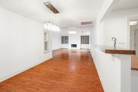 a view of a kitchen with kitchen island a sink wooden floor and a chandelier