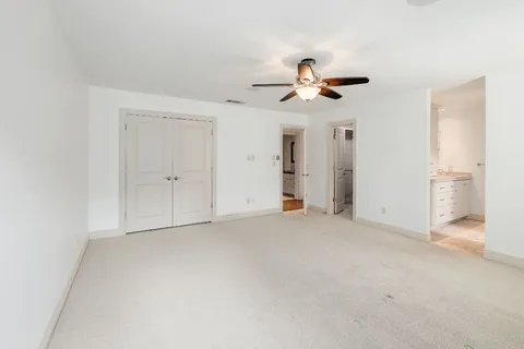 an empty room with chandelier fan and windows