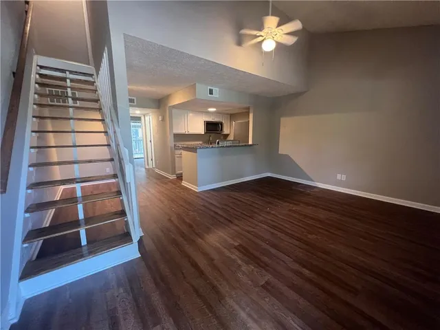 a view of a livingroom with wooden floor and a ceiling fan