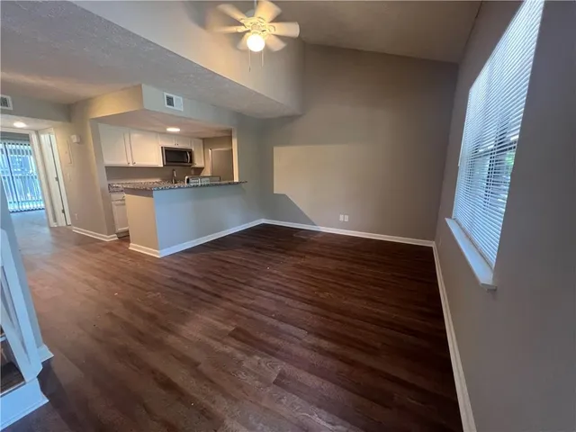 a view of kitchen and empty room with wooden floor