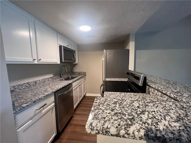 a kitchen with granite countertop a sink and cabinets