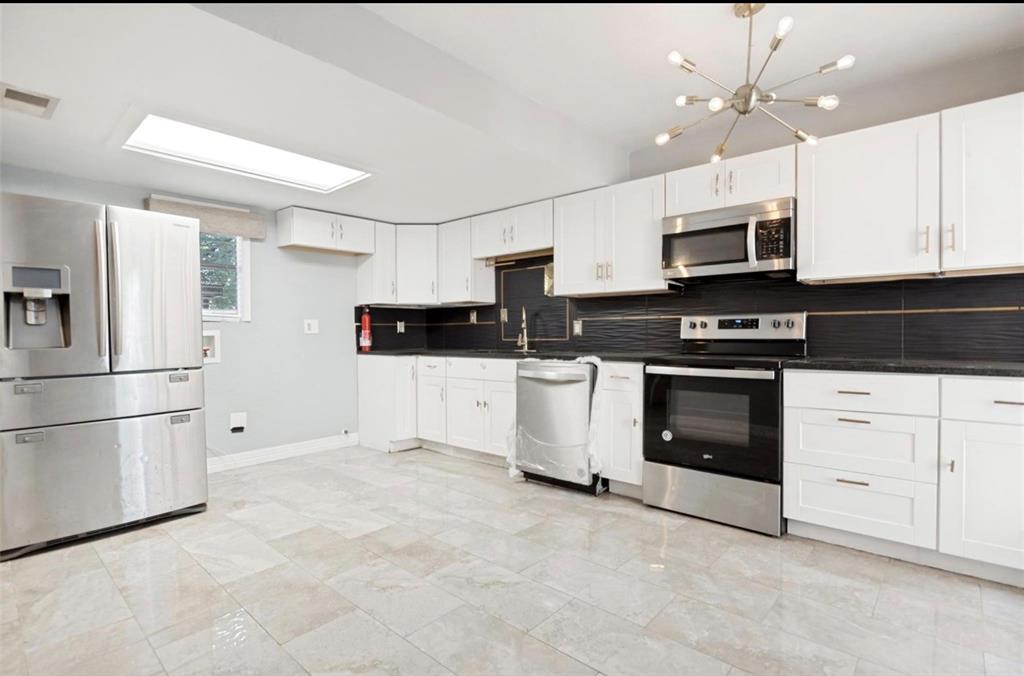 5808 Harvest Hill Road Dallas, TX 75230 - Photo 7 of 18 Modern kitchen featuring white cabinetry, stainless steel appliances, dark countertops, a textured dark backsplash, and light tile flooring