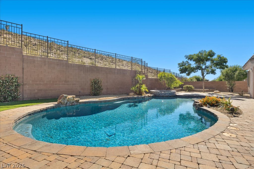 2125 De Rouge Avenue Henderson, NV 89044 - Photo 80 of 96 A tranquil oasis featuring a sparkling in-ground pool, spa, and pavers, perfect for enjoying warm days.