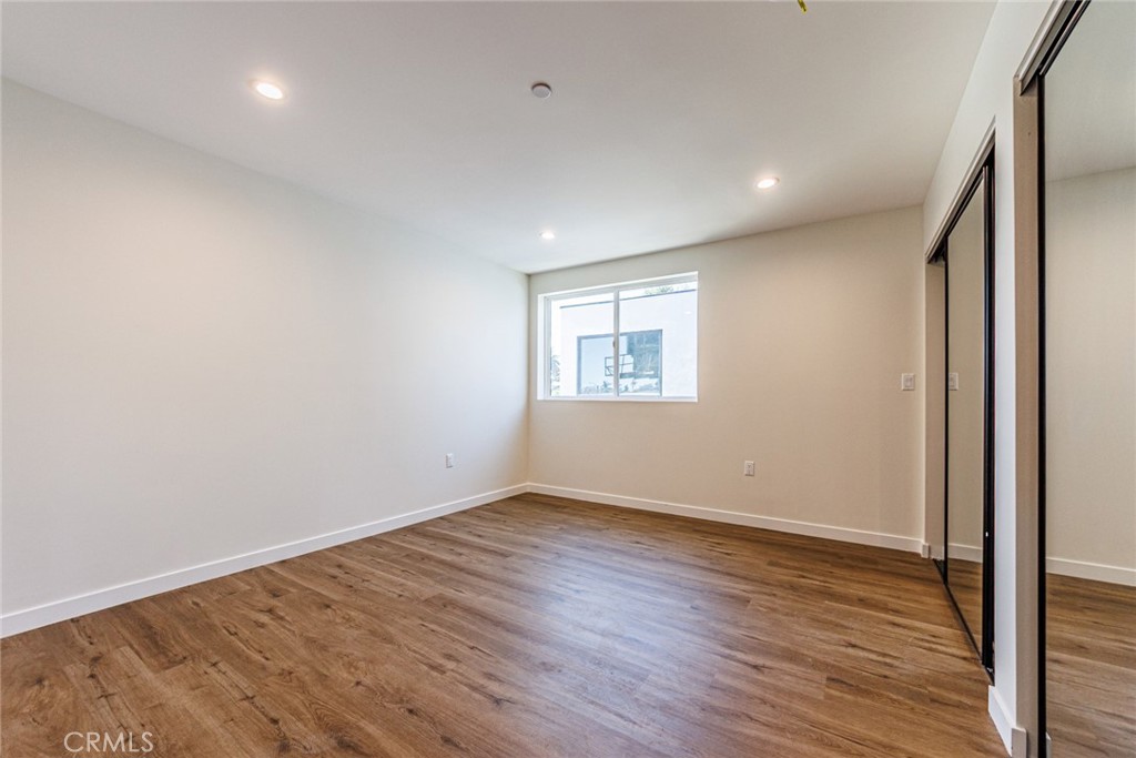 1857 Crenshaw Boulevard, Unit 1/2 Los Angeles, CA 90019 - Photo 22 of 24 an empty room with wooden floor and windows