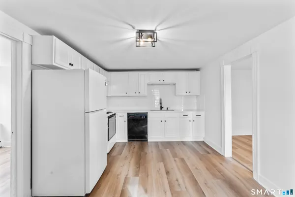 a kitchen with a refrigerator a sink and dishwasher with white cabinets