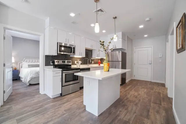 a kitchen with kitchen island white cabinets and stainless steel appliances