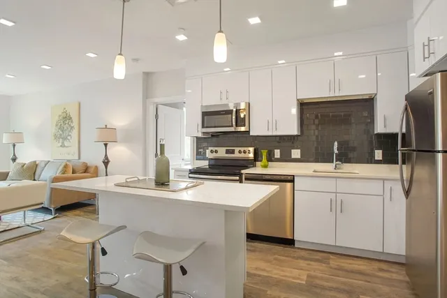 a kitchen with stainless steel appliances granite countertop a sink a stove a refrigerator and island with wooden floor