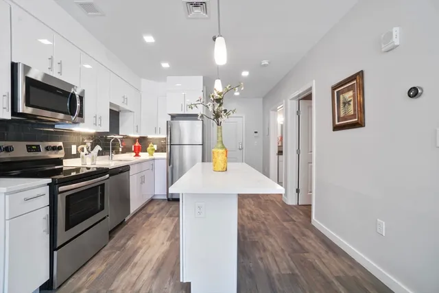 a kitchen with stainless steel appliances kitchen island granite countertop a stove a sink a refrigerator and a microwave