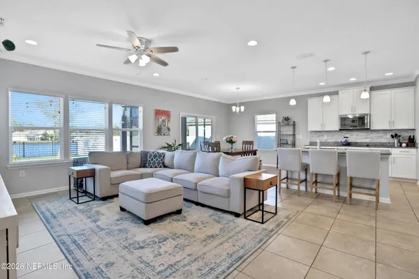 a living room with couches and kitchen view with wooden floor