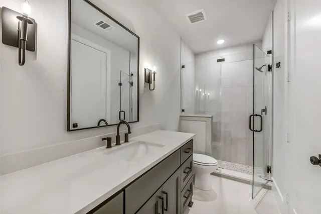 a bathroom with a sink toilet double vanity and shower