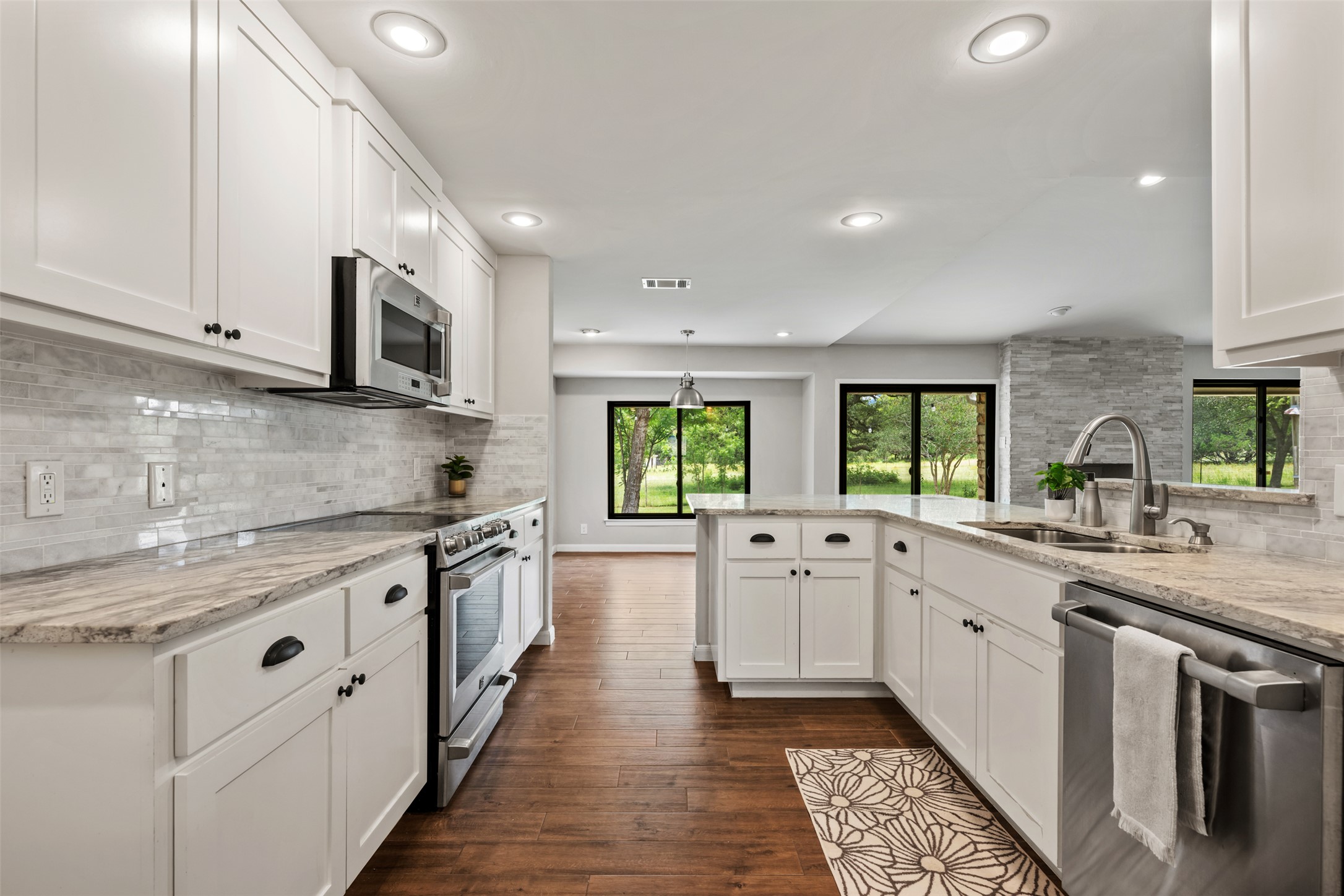 1600 Pin Oak Lane Round Rock, TX 78681 - Photo 19 of 40 Bright kitchen featuring white shaker cabinetry, stainless steel appliances, marble-look countertops, a mosaic tile backsplash, and dark wood-finish flooring