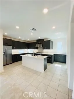 a large white kitchen with kitchen island a sink a counter top stainless steel appliances and cabinets