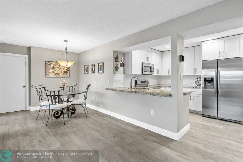 a kitchen with stainless steel appliances kitchen island hardwood floor and dining table