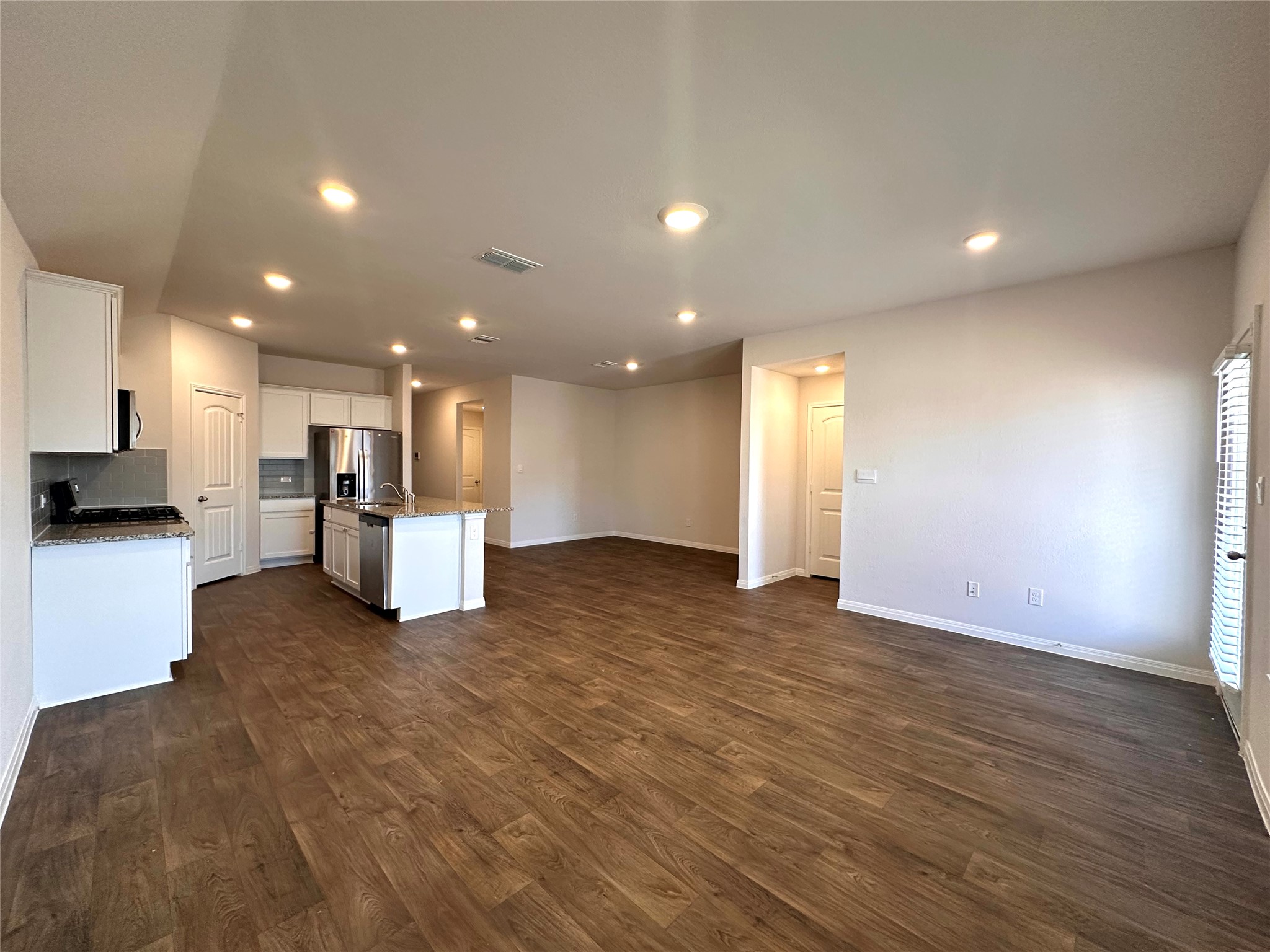 13804 Thomas Wheeler Way Manor, TX 78653 - Photo 27 of 27 Kitchen with open floor plan, white cabinetry, recessed lighting, dark wood finished floors, and a kitchen island with sink