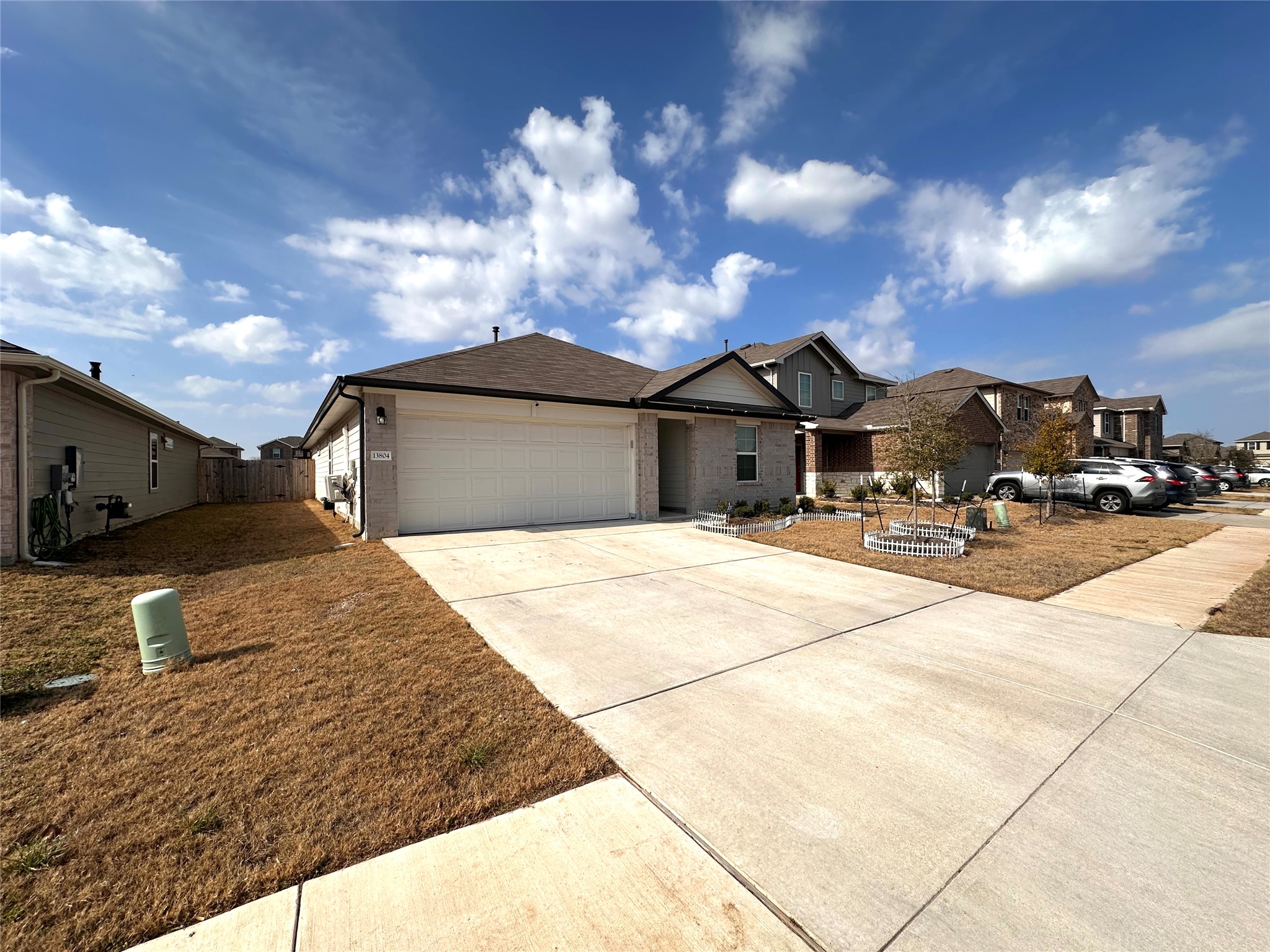 13804 Thomas Wheeler Way Manor, TX 78653 - Photo 2 of 27 View of front of home featuring concrete driveway, a garage, a residential view, and brick siding
