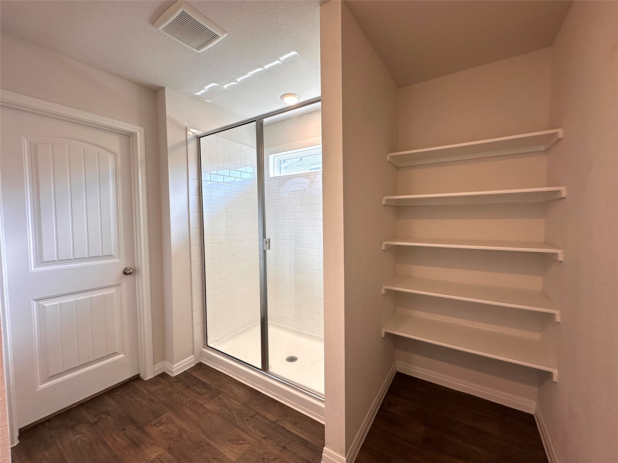 13804 Thomas Wheeler Way Manor, TX 78653 - Photo 19 of 27 Bathroom with a stall shower, dark wood-style floors, and a textured ceiling