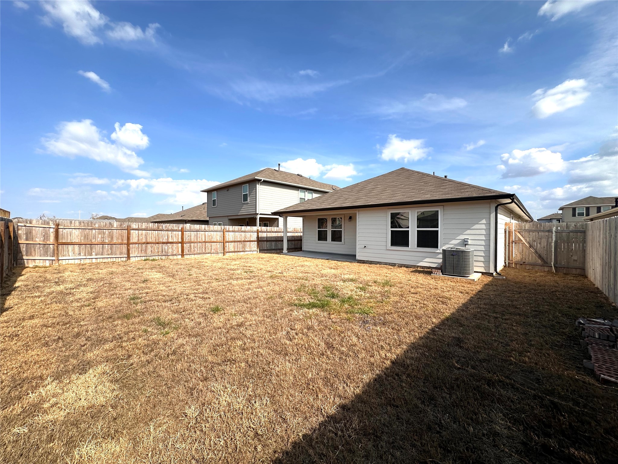 13804 Thomas Wheeler Way Manor, TX 78653 - Photo 24 of 27 Rear view of house featuring a fenced backyard, a gate, and roof with shingles