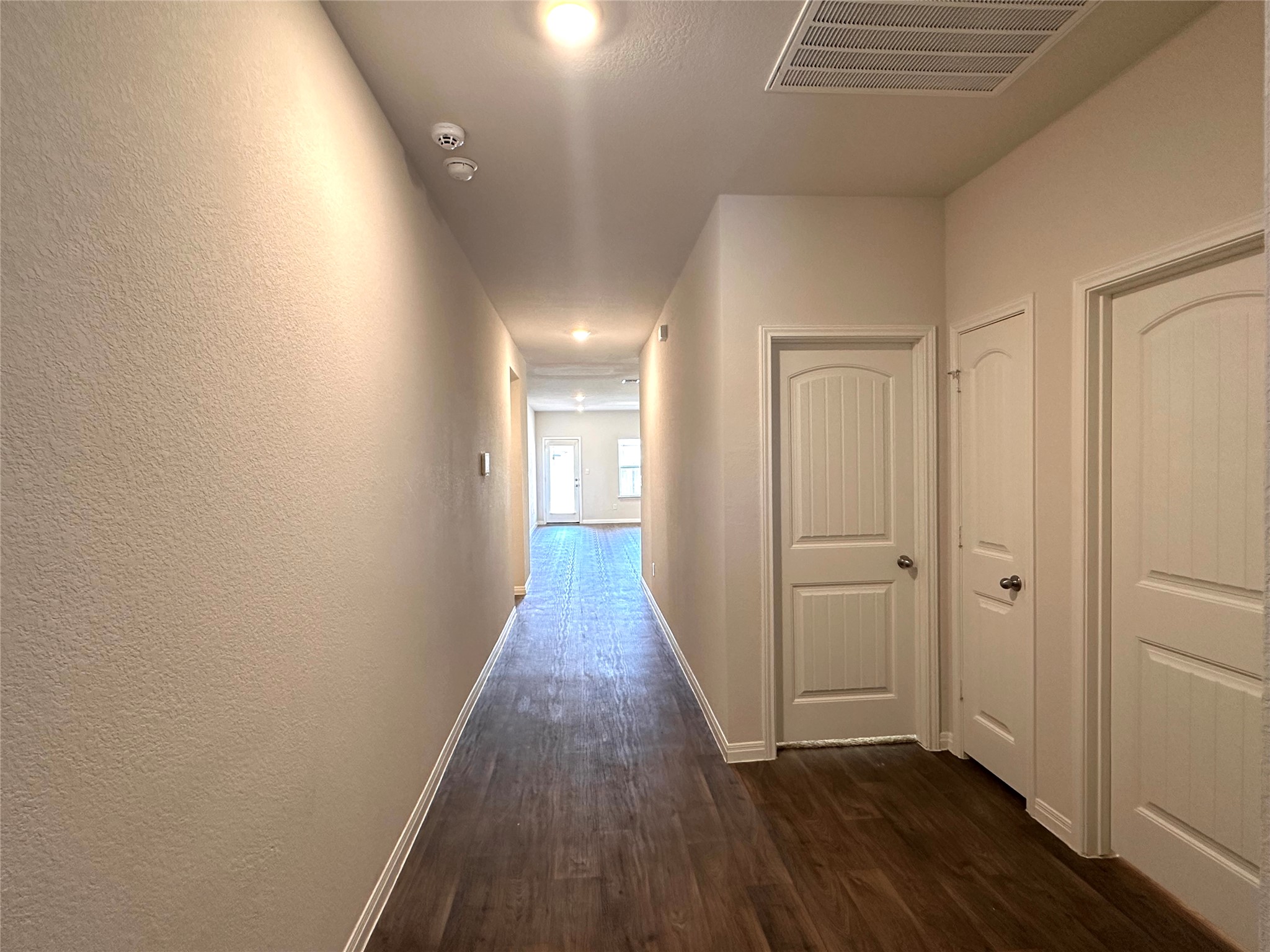 13804 Thomas Wheeler Way Manor, TX 78653 - Photo 5 of 27 Hallway with dark wood-style floors and a textured wall