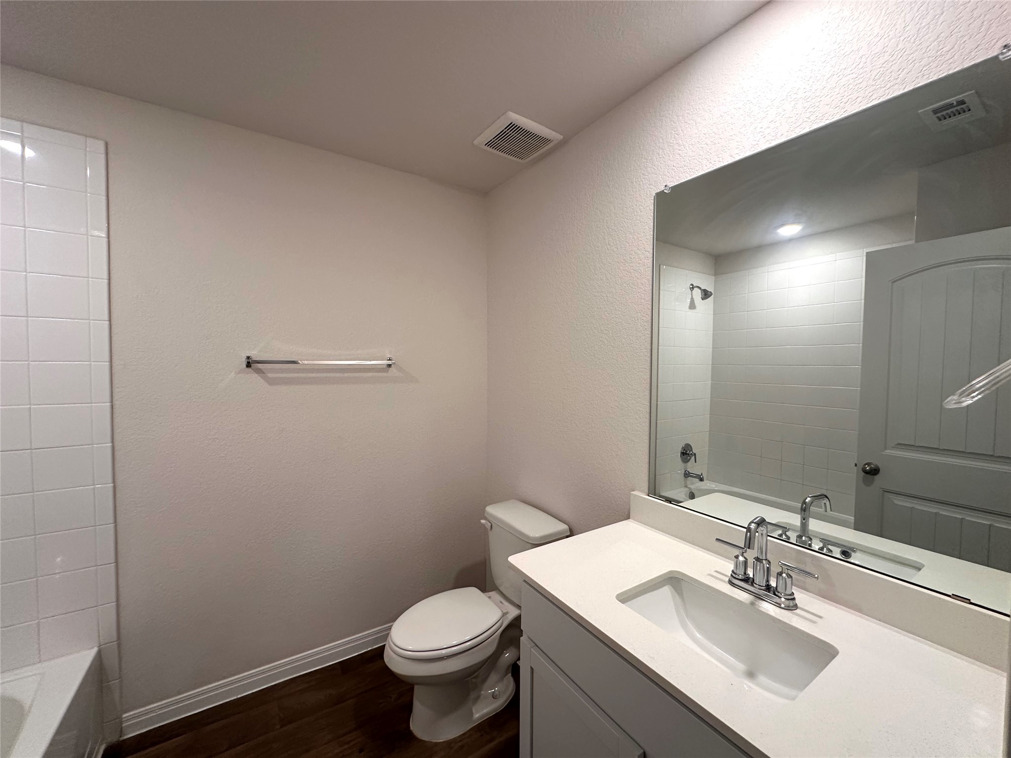 13804 Thomas Wheeler Way Manor, TX 78653 - Photo 7 of 27 Bathroom with shower / bathtub combination, a textured wall, vanity, and dark wood finished floors