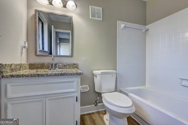 a bathroom with a granite countertop toilet sink and mirror