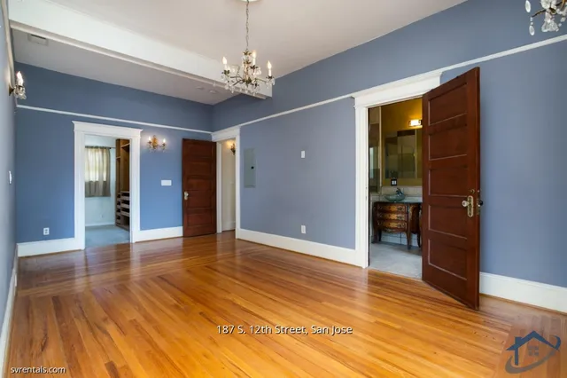 a view of an empty room with wooden floor and a chandelier