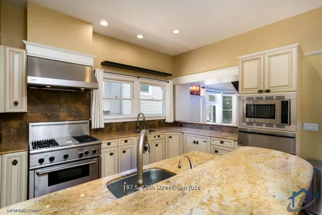 a kitchen with stainless steel appliances kitchen island granite countertop a sink stove and microwave