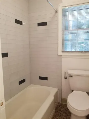 a white toilet sitting next to a bath tub