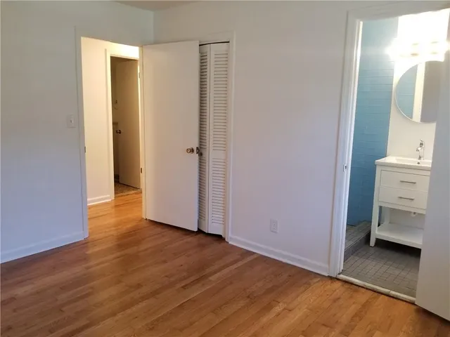 a view of an empty room with wooden floor and closet
