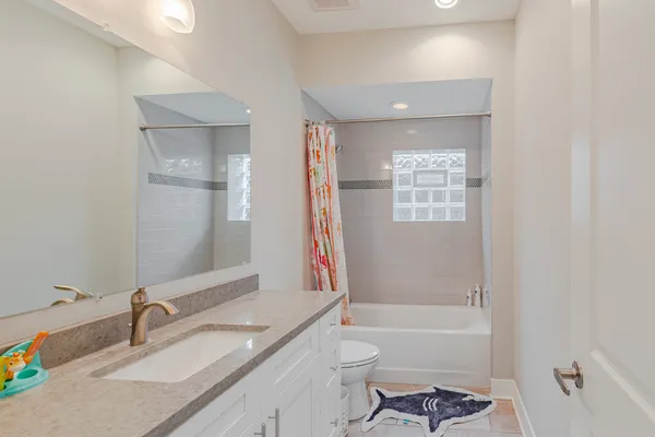 a bathroom with a granite countertop sink a toilet and shower