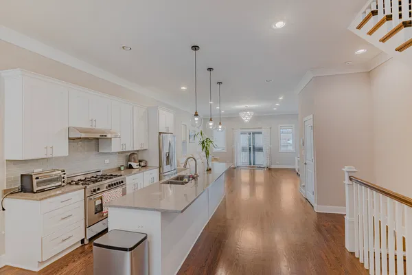 a large kitchen with granite countertop a large counter top a sink stainless steel appliances and cabinets