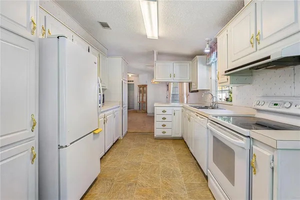 a kitchen with granite countertop white cabinets and white appliances