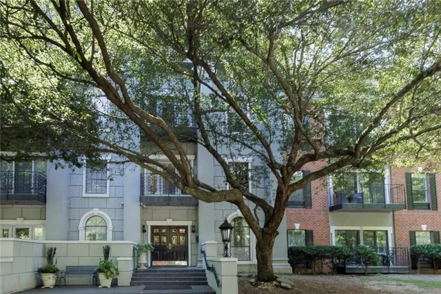 a front view of a house with garden and trees