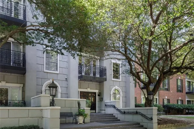 a front view of a house with garden and trees