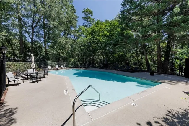 a view of swimming pool with seating area and trees