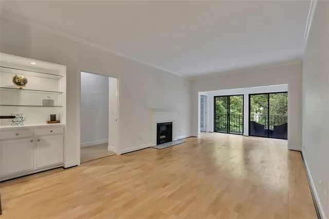 a view of an empty room with window and wooden floor