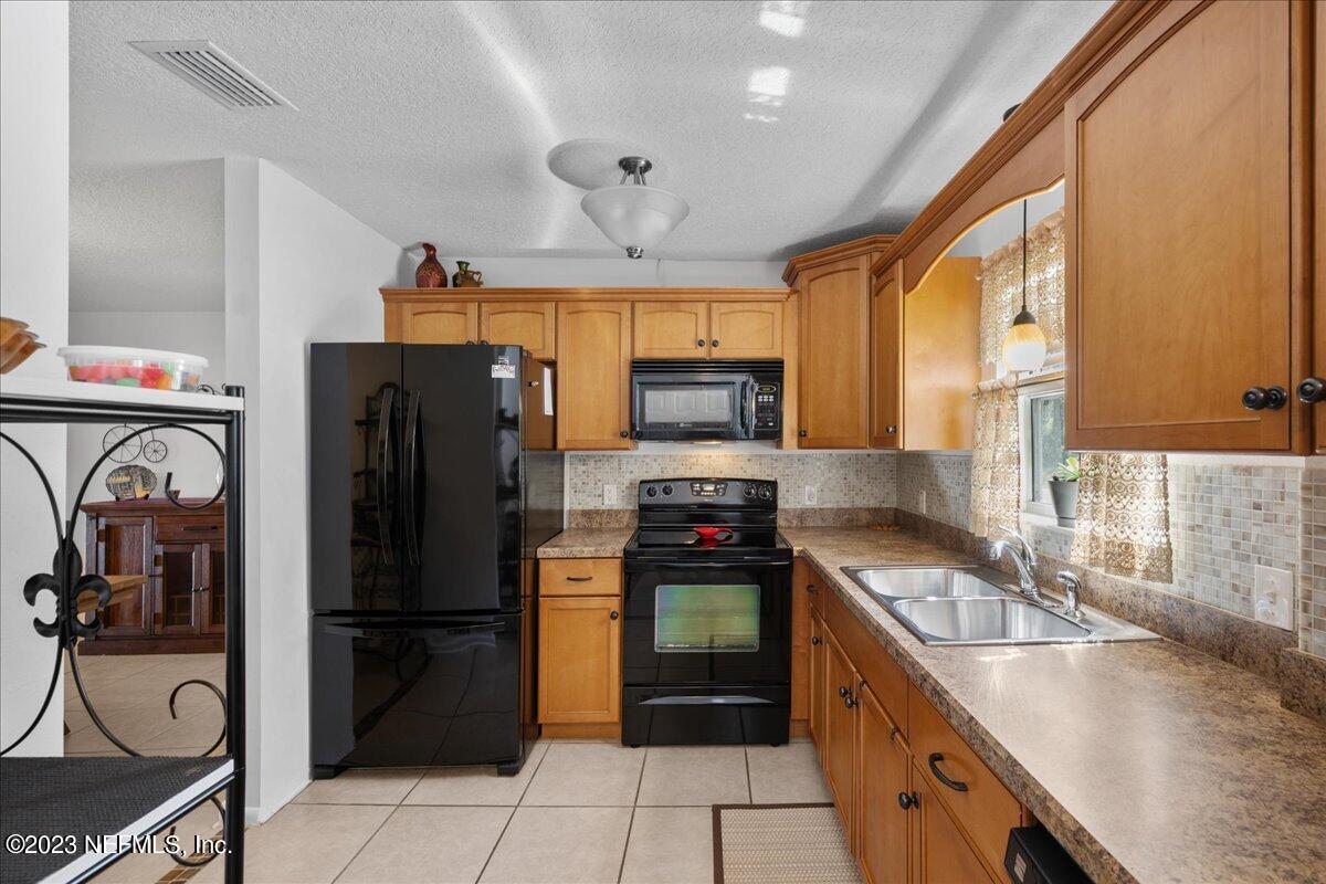 113 Leaf Street San Mateo, FL 32187 - Photo 11 of 32 a kitchen with stainless steel appliances granite countertop a refrigerator a stove a sink and a microwave