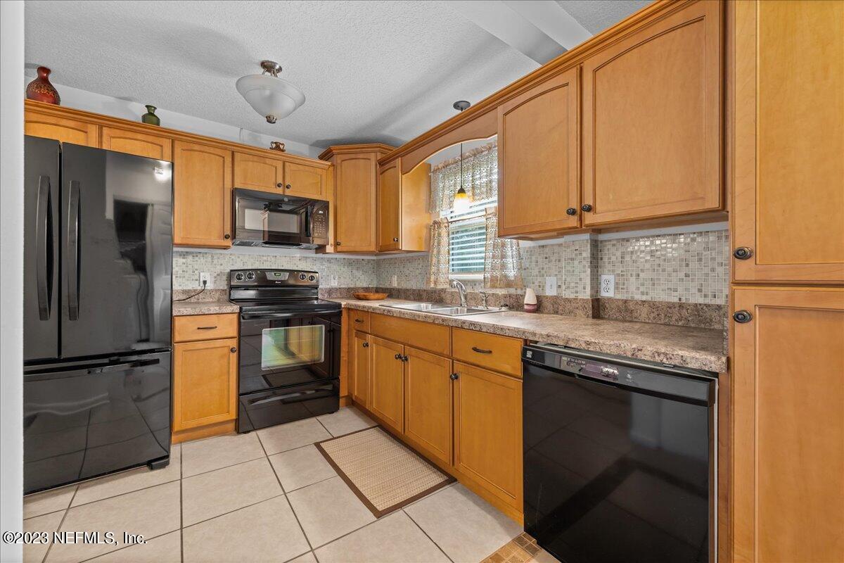 113 Leaf Street San Mateo, FL 32187 - Photo 9 of 32 a kitchen with stainless steel appliances granite countertop a refrigerator a sink dishwasher a stove with wooden cabinets and floor
