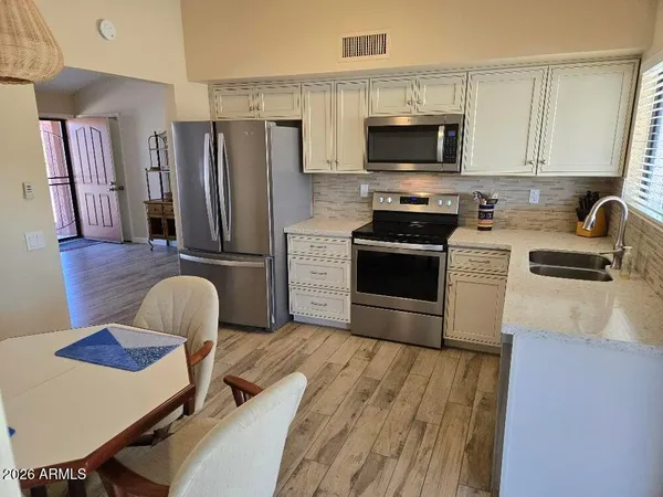 a kitchen with stainless steel appliances a stove a sink dishwasher a refrigerator microwave and cabinets