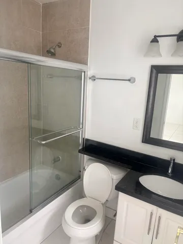 a bathroom with a granite countertop sink mirror vanity and toilet